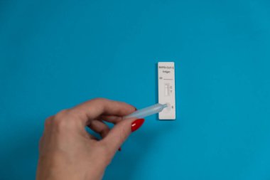 Kadın eli mavi arka planda Test Hızlı Antijen SARS-CoV-2 yapıyor. SARS-CoV-2 virüsünün antijenleri negatif..