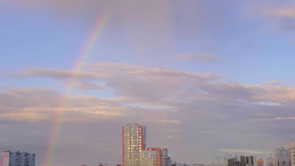 Arc-en-ciel multicolore et nuages dans le ciel après la pluie et des bâtiments de plusieurs étages dans la ville, abstraction, flou — Video