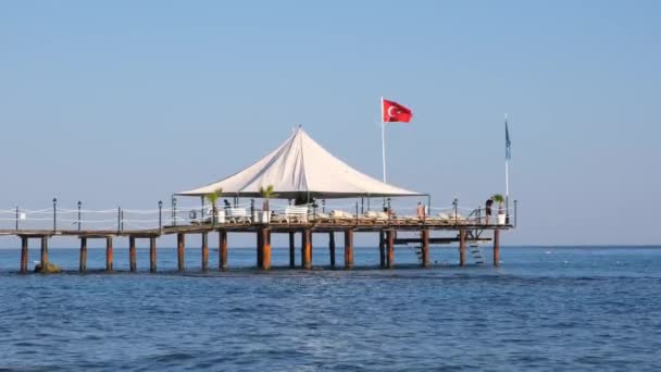 Petite jetée en bois sur la plage de bardeaux et l'eau d'aquamarine dans la station touristique populaire de Côté sur la mer Méditerranée en Turquie — Video