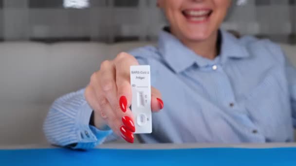 Feminino segurando negativo SARS-CoV-2 teste rápido de antígeno em fundo azul — Vídeo de Stock