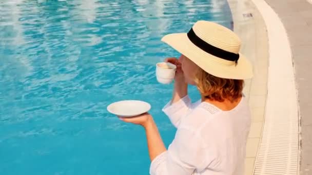 Idealna koncepcja luksusowego życia. rano kobieta w słomkowym kapeluszu pije kawę w pobliżu niebieskiego basenu — Wideo stockowe