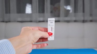 Mavi arka planda kadın eli Negatif SARS-CoV-2 Hızlı Antijen Testi