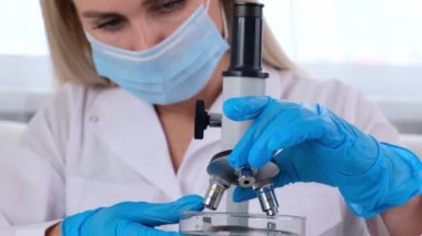Genç bilim adamı laboratuvar asistanı laboratuvardaki mikroskoba bakıyor. Genç bir bilim adamı araştırma yapıyor..