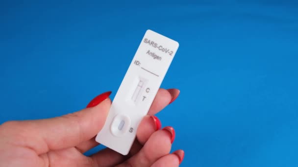 Weibliche Hand hält negativen SARS-CoV-2 Antigen-Schnelltest auf blauem Hintergrund — Stockvideo
