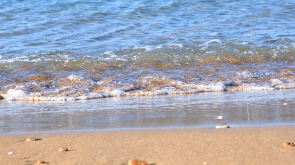 Zachte golf van de blauwe zee op het zandstrand op een zomerse zonnige dag. — Stockfoto