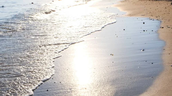 Zachte golf van de blauwe zee op een zandstrand met een zonneschijn bij zonsondergang — Stockfoto