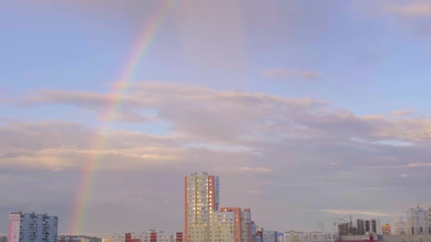 Flerfärgad regnbåge och moln på himlen efter regn och flervåningshus i staden, abstraktion, suddig — Stockvideo