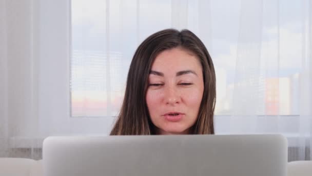 女性博主一边笑一边在笔记本电脑上与朋友聊天，在合作空间中使用无线网络。在网站上网上购物的积极年轻女性 — 图库视频影像