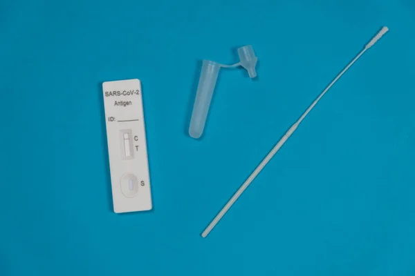 Kit de teste de antígeno. Teste de antígeno rápido SARS-CoV-2 negativo isolado em fundo azul com bastão de esfregaço nasal — Fotografia de Stock
