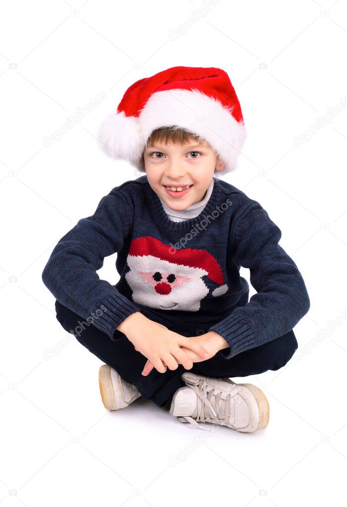Cute little boy with Santa hat sitting on studio white background