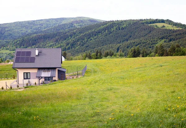 Small house, solar panels as renewable source of energy. Mountain Village in summer afternoon. Solar panels on roof of house in high mountains. Copy space. CONCEPTS OF ECOLOGY