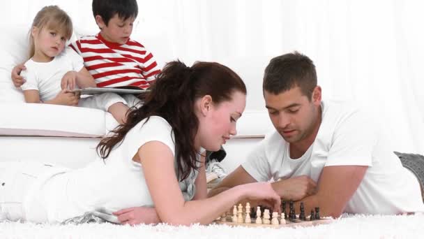 Молодая пара играет в шахматы в гостиной — стоковое видео