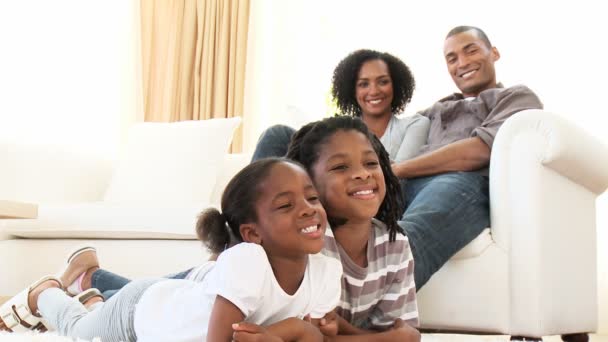 Afroamerikanische Kinder sehen mit ihren Eltern im Wohnzimmer einen Film — Stockvideo