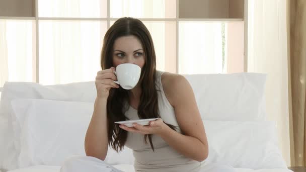 Schöne Frau trinkt eine Tasse Kaffee im Bett — Stockvideo