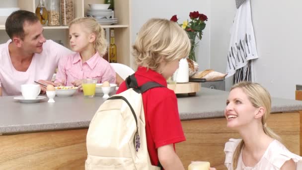Mutter gibt ihrem Sohn das Schulessen in der Küche — Stockvideo