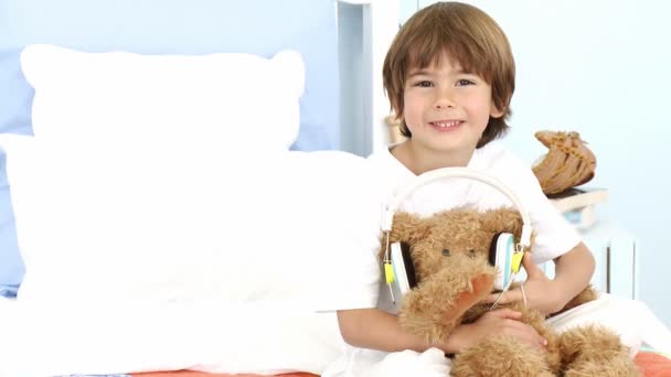 Kleine jongen en teddy beer luisteren naar muziek op bed — Stockvideo