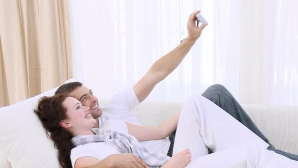 Casal sentado em um sofá tirando uma foto — Vídeo de Stock
