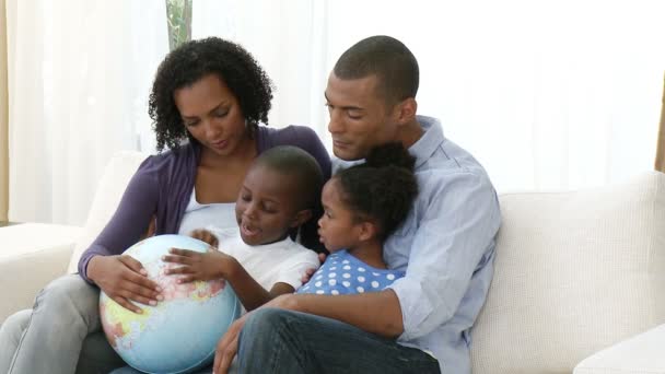 Familia joven afroamericana sosteniendo un globo terrestre — Vídeo de stock