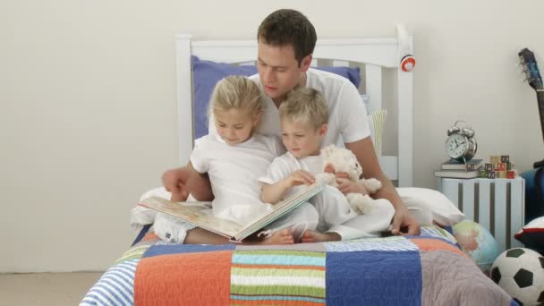 Papá leyendo con sus hijos en el dormitorio — Vídeos de Stock