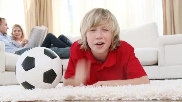 Ребенок смотрит футбольный матч по телевизору на полу — стоковое видео