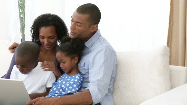 Panorama de la famille afro-américaine utilisant un ordinateur portable sur le canapé — Video