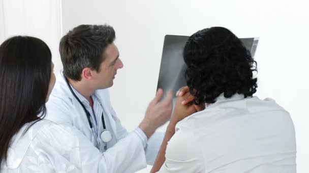 Arzt erklärt einem Patienten im Büro ein Röntgenbild — Stockvideo