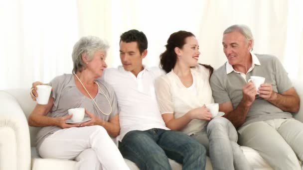 Родители, бабушка и дедушка пьют кофе на диване — стоковое видео
