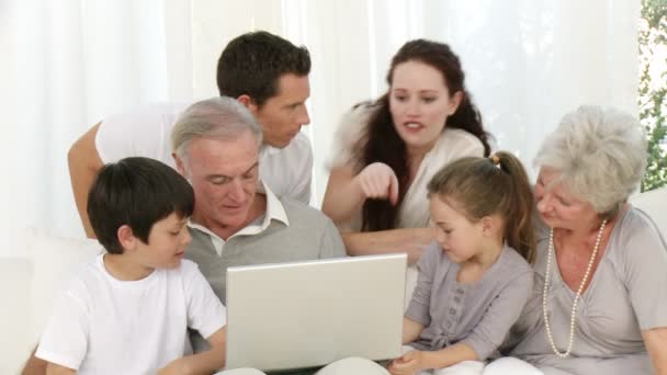 Parents, grands-parents et enfants assis sur le canapé à l'aide d'un ordinateur portable — Video