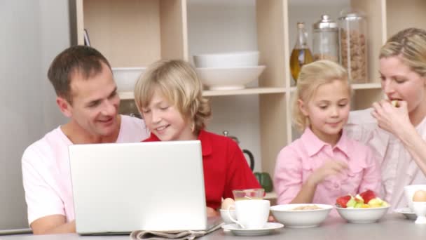 Famiglia che fa colazione e utilizza un computer portatile in cucina — Video Stock