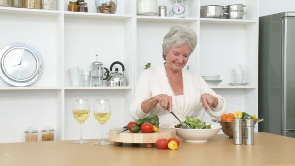 Glückliches Seniorenpaar bereitet in der Küche einen Salat zu — Stockvideo