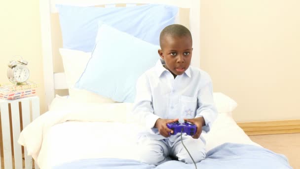 アフリカ系アメリカ人の小さな男の子が彼の寝室でビデオ ゲームをプレイ — ストック動画