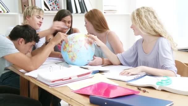 Adolescentes em uma biblioteca trabalhando com um globo terrestre — Vídeo de Stock