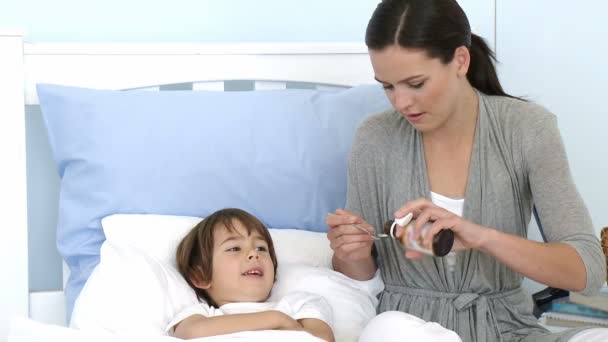 Мать дает своему сыну лекарство от кашля — стоковое видео