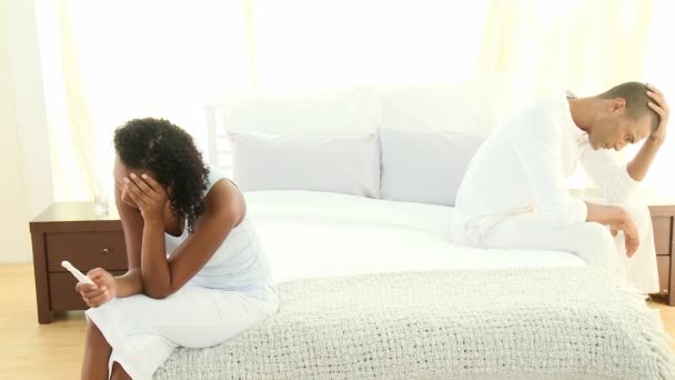 Upset Afro-American couple in bedroom holding a pregnancy test — Stock Video