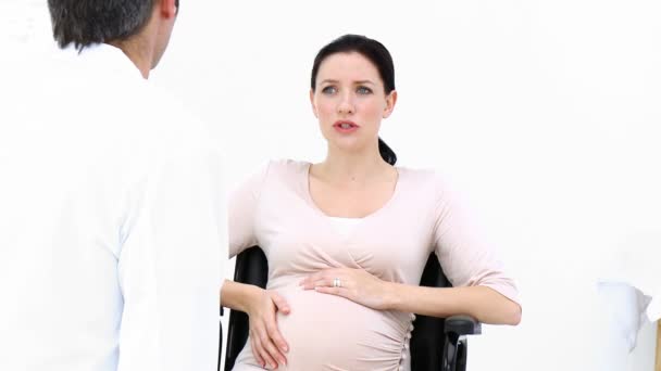 Pregnant woman sitting on wheelchair talking with a doctor — Stock video