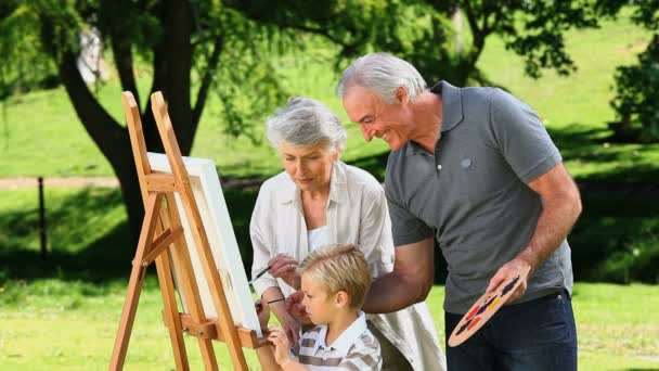 Jeune garçon peignant une toile avec des grands-parents — Video