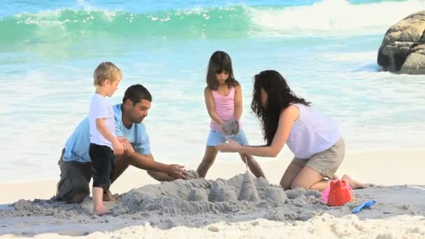 Familia construyendo un castillo de arena — Vídeos de Stock