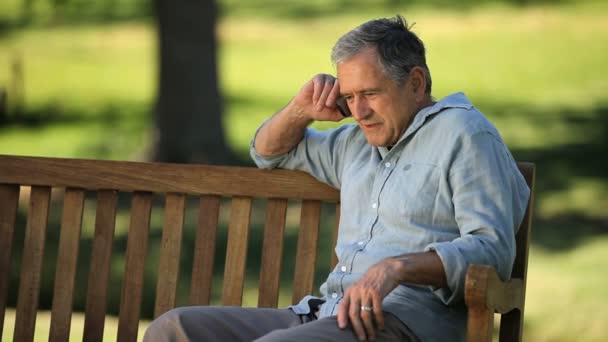 Senior man talking on the phone on a bench — Stock Video