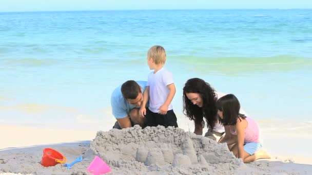 Familia alegre construyendo un castillo de arena — Vídeo de stock