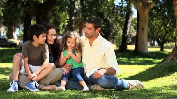 Linda familia disfrutando del tiempo juntos sentados en la hierba — Vídeo de stock