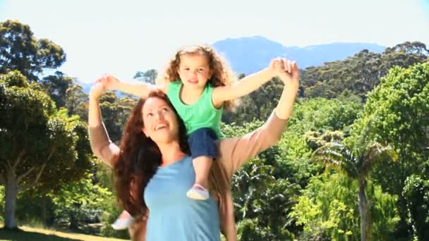 彼女の肩に彼女の娘を運ぶ女性 — ストック動画