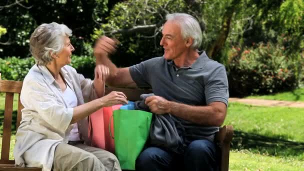 Senior couple looking at clothes after shopping on a bench — Stock Video