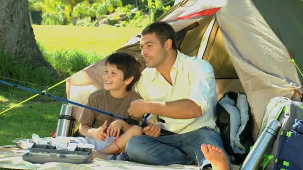 Apja oktatás használja a horgászbotot, a fia, a sátor előtt ülve — Stock videók