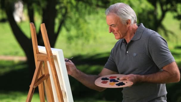 Viejo pintando un lienzo — Vídeo de stock