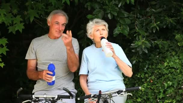 Couple de personnes âgées avec des vélos prenant une pause pour boire — Video