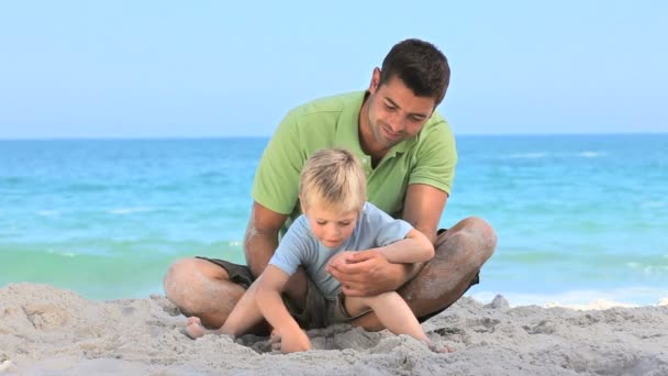 Père et fils jouant avec le sable — Video