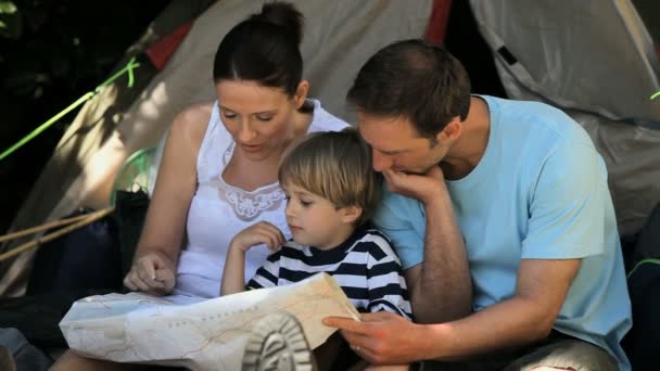Семья смотрит на карту возле палатки — стоковое видео