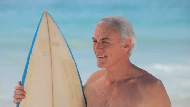 Closeup of a senior man looking at the ocean with a surfboard — Stock Video