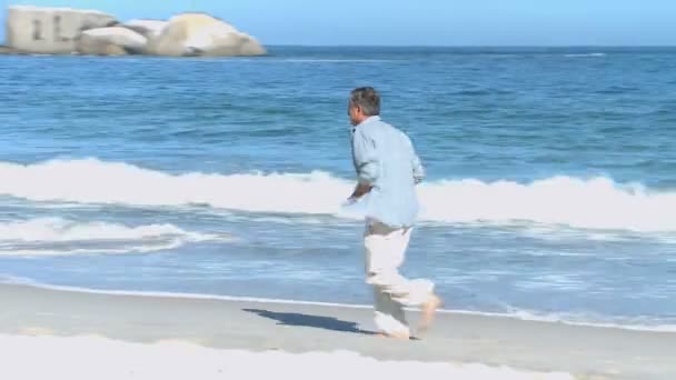 Man loopt langs het strand — Stockvideo