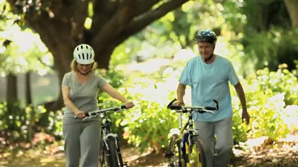 Senior koppel wandelen en fietsen duwen — Stockvideo